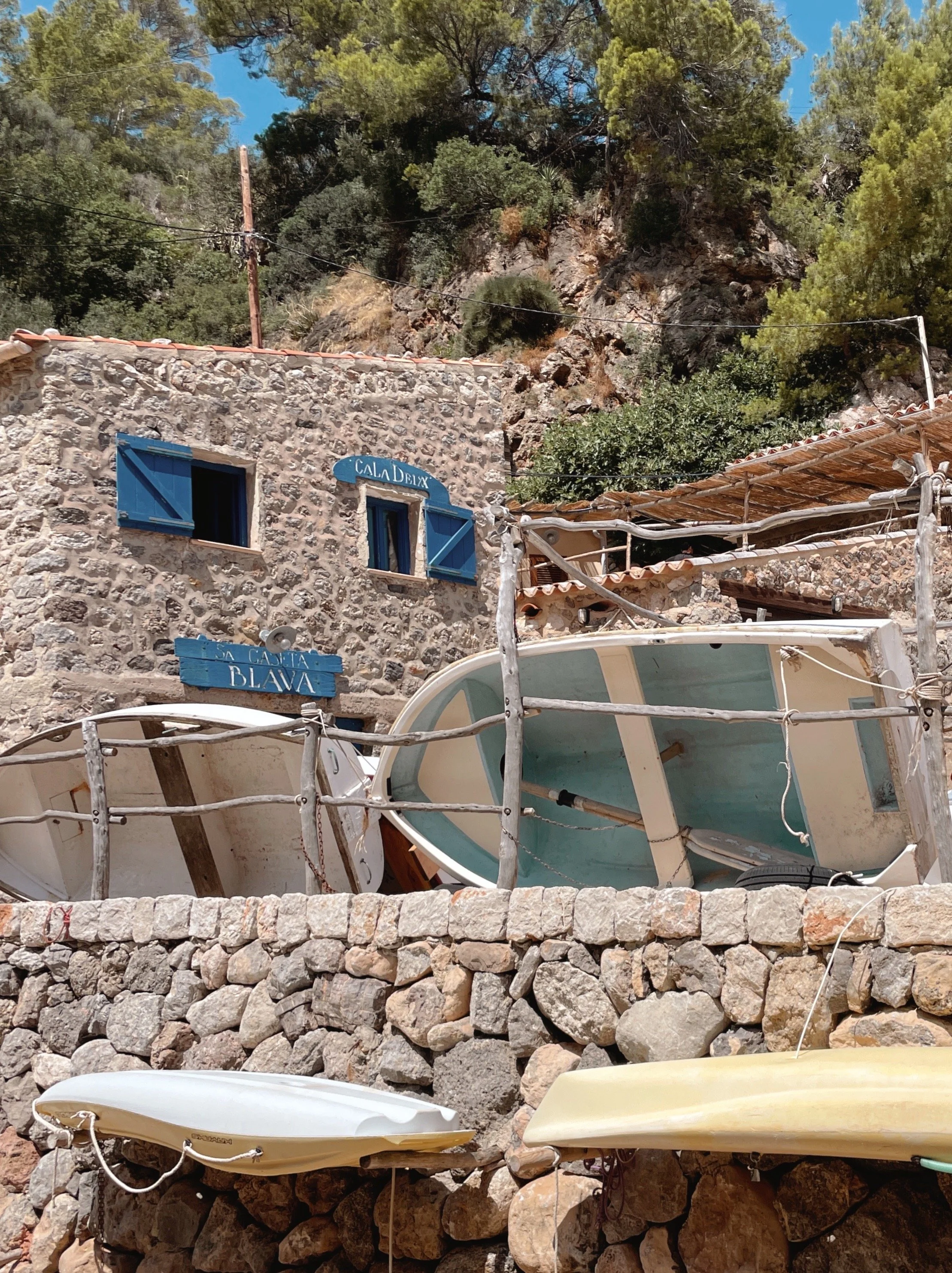 Faded pastel dinghies stacked up at Cala Deiá, Mallorca