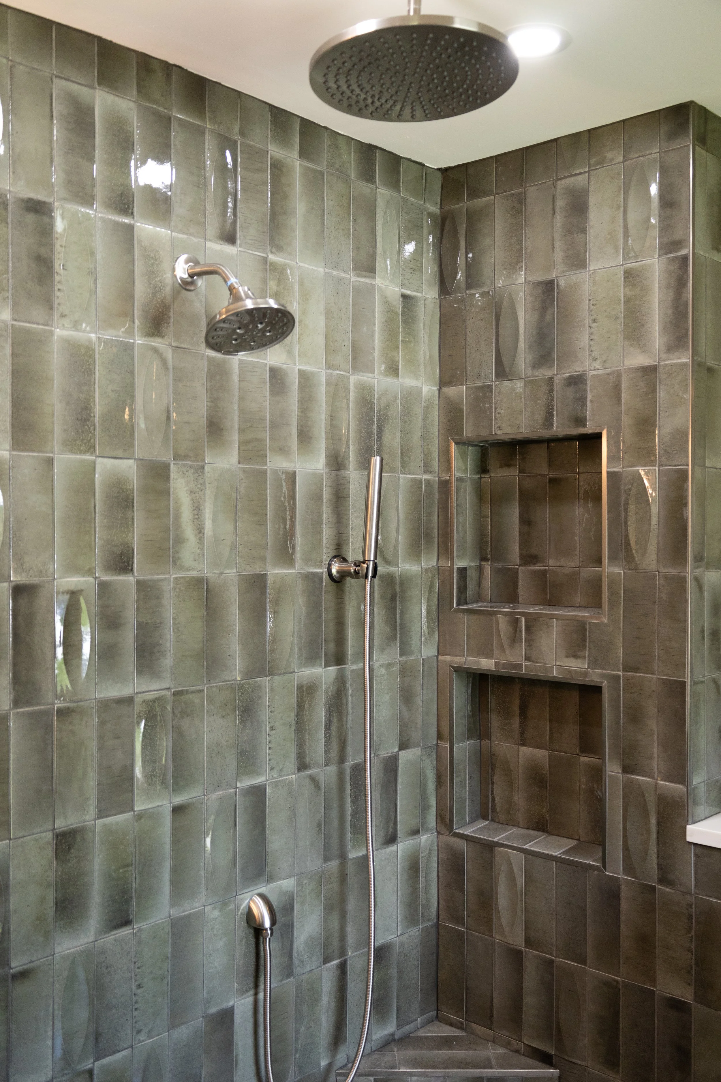 Luxury master shower with tiled walls, a round overhead rain shower head, a handheld shower head, and a built-in tiled shelf in Dayton TN. 