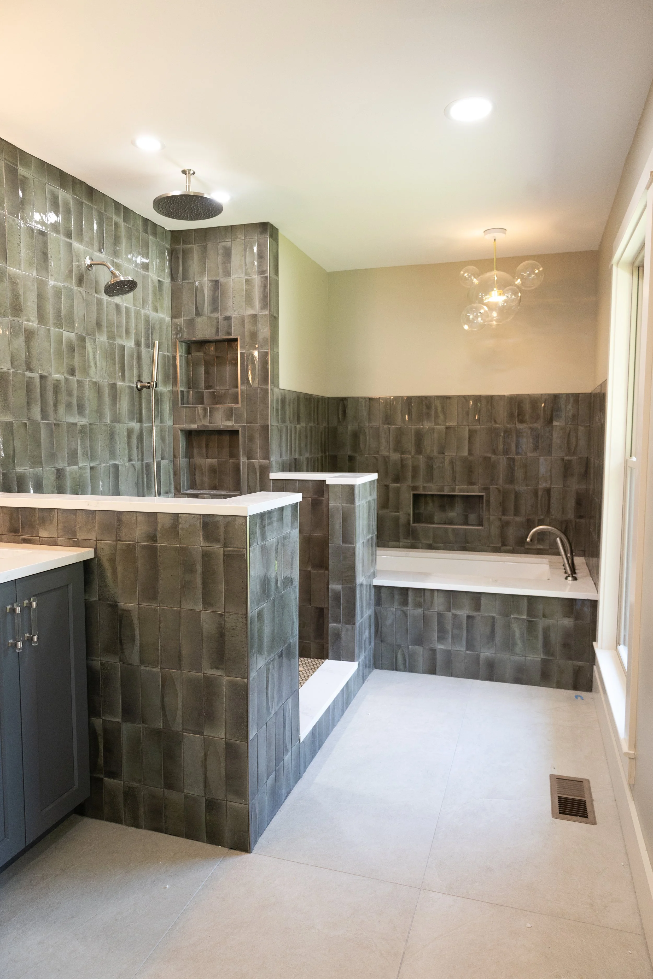 Ultra-luxury green and grey master shower layout transformation in Dayton TN, boasting a built-in deep soaking bath architecture and ceiling mounted cascading rain showerhead with flawless stone symmetry.