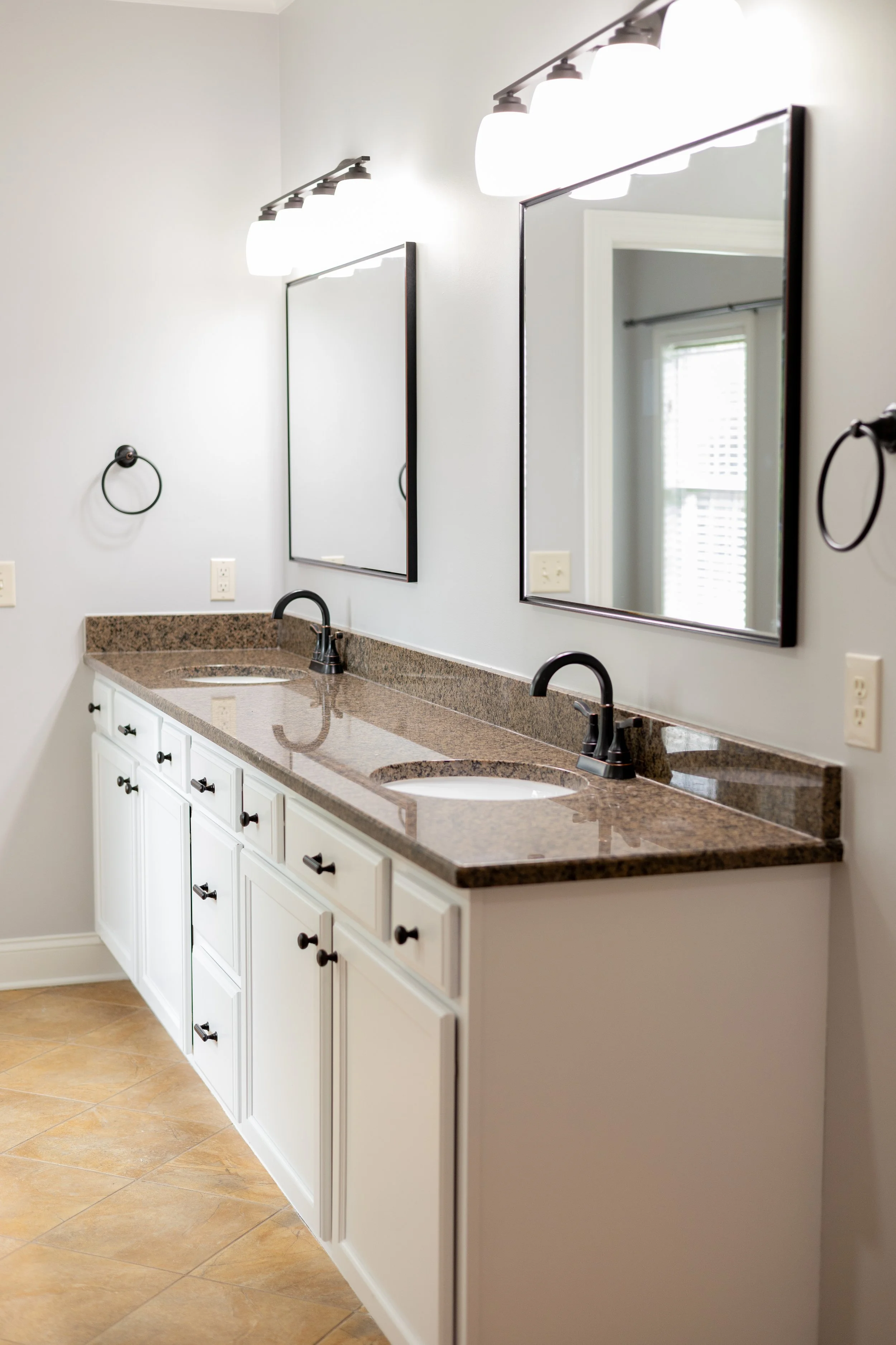 High-ROI residential bathroom upgrade in Ooltewah TN, featuring a his-and-hers vanity with crisp white cabinetry, modern vanity mirrors, and contemporary matte black fixtures engineered to maximize property resale value. 
