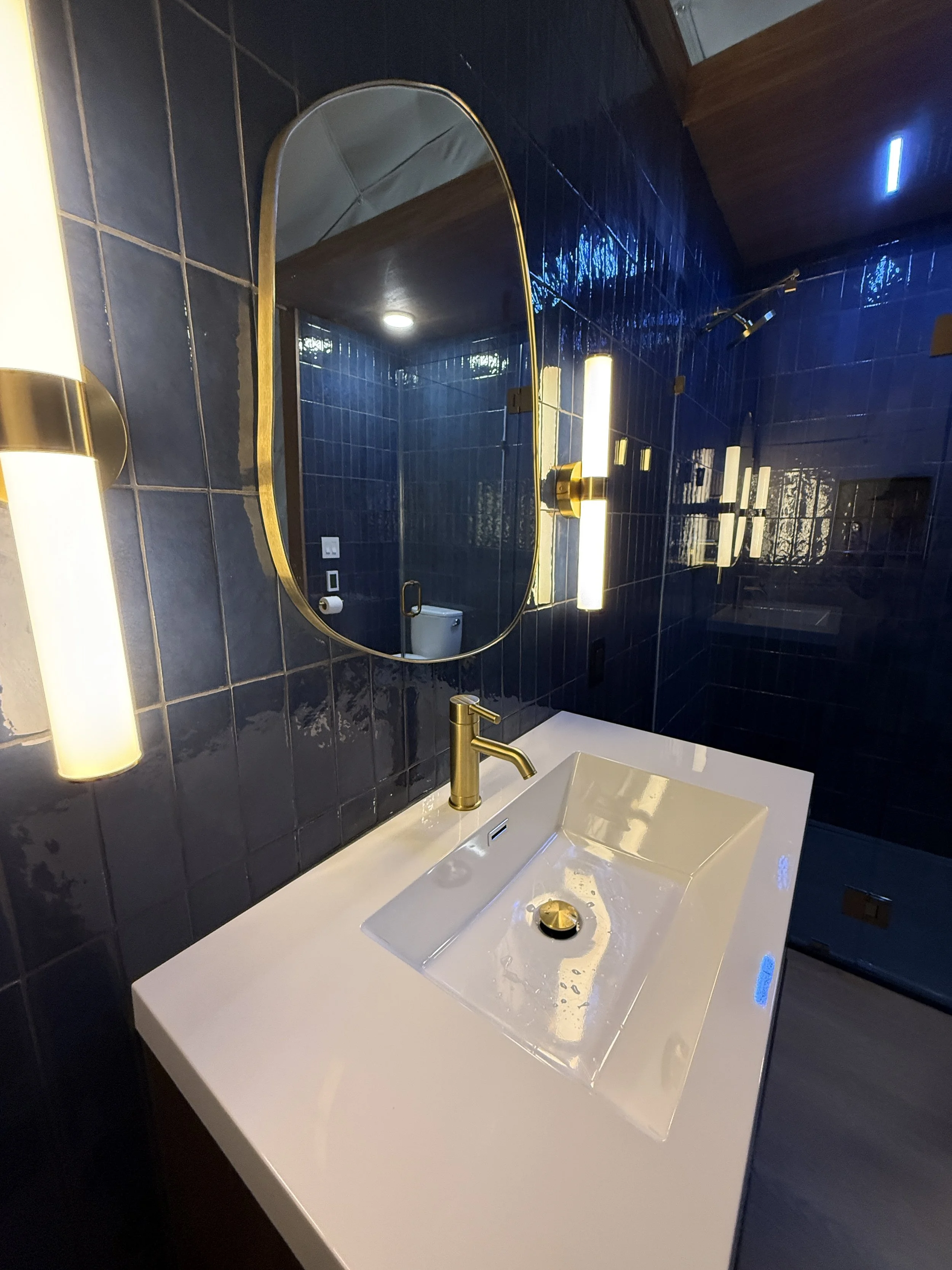 Bespoke bathroom by Mims Construction in Trenton GA, highlighting a premium custom glass-enclosed walk-in shower framed by continuous blue tile walls and an upscale custom yurt vanity installation.