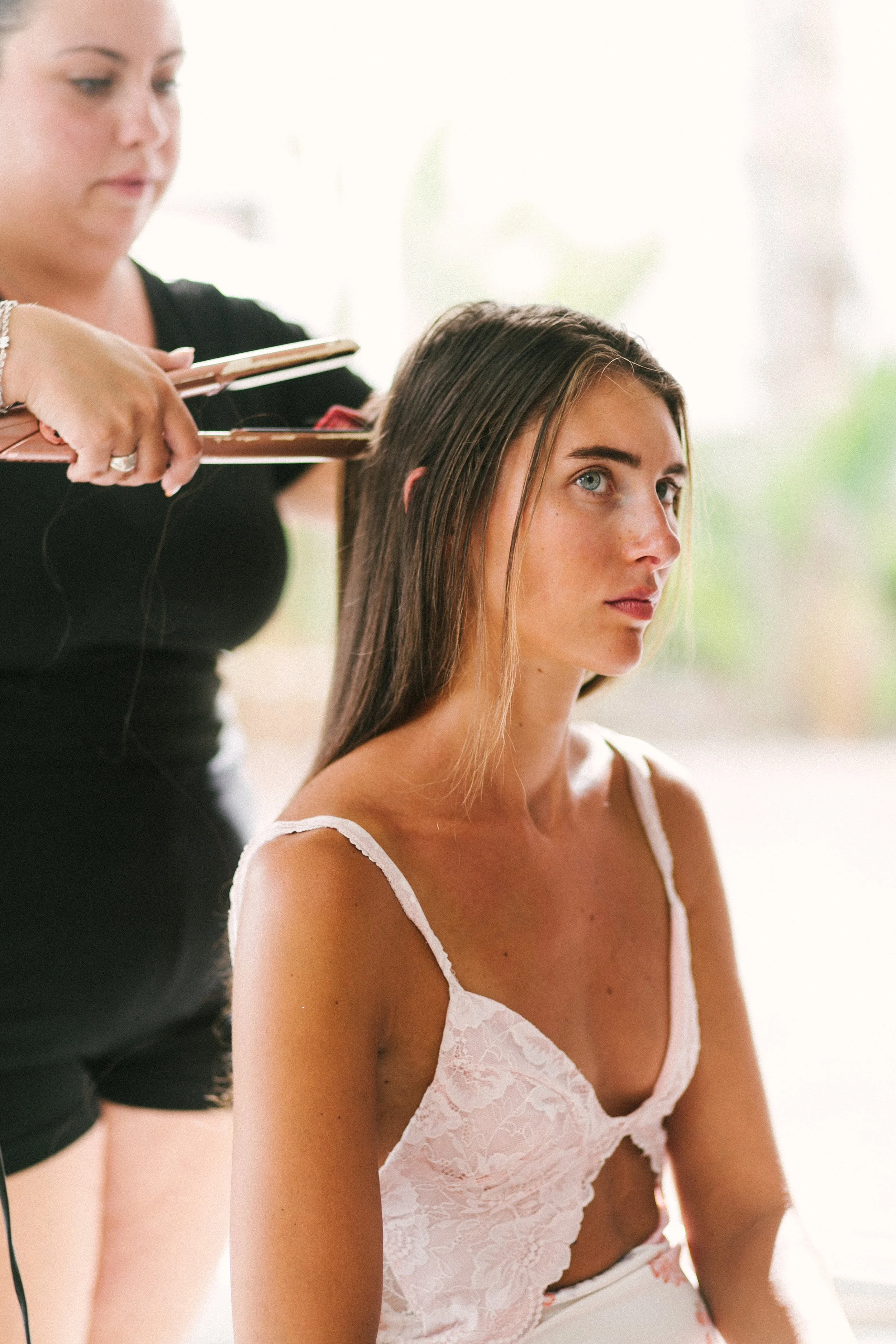 A woman getting her hair styled by a hairstylist in a bright room.