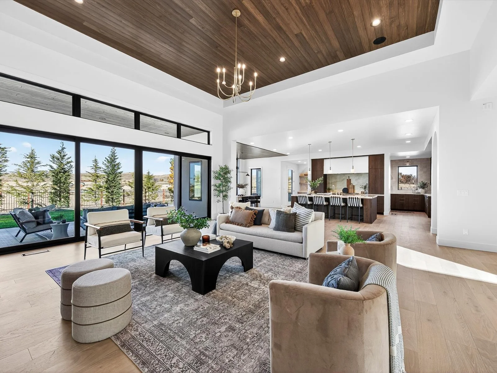 Open-concept living room and kitchen with large sliding glass doors, modern furniture, and wood accents.