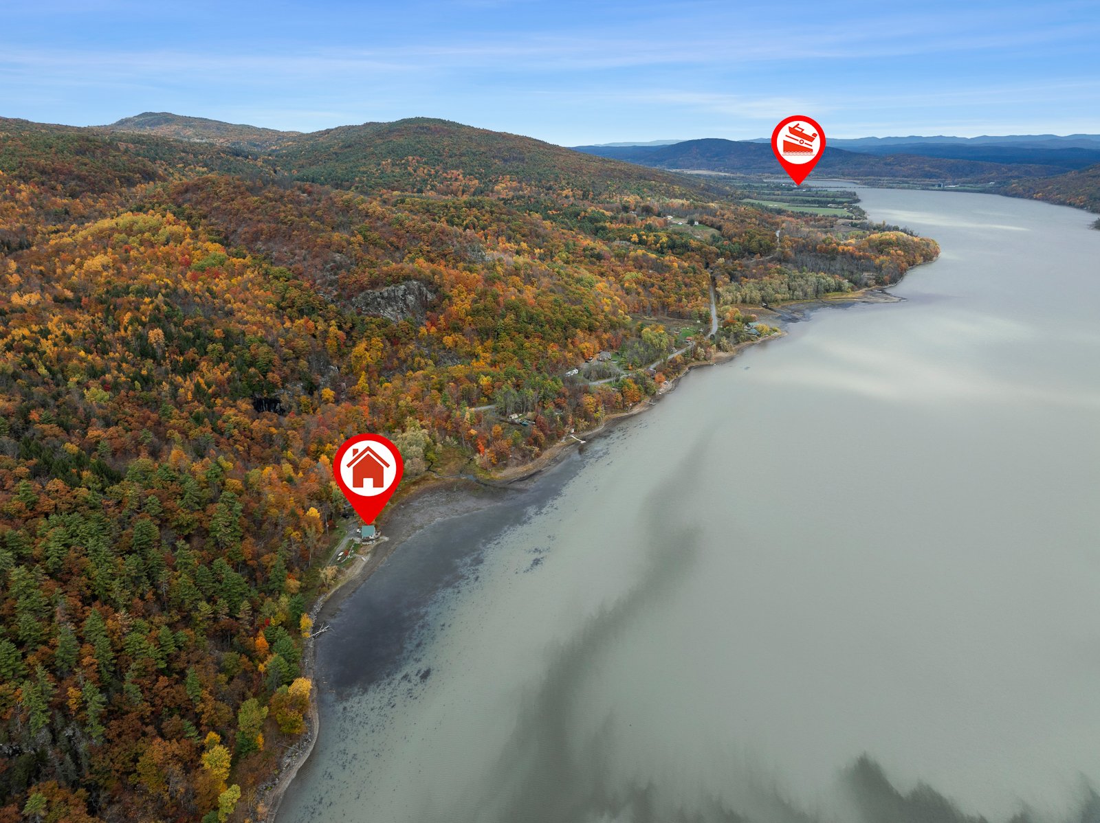 Aerial view of a lake with autumn-colored trees along the shoreline, showing two red icons: a house near the shore and a boat farther out on the water.