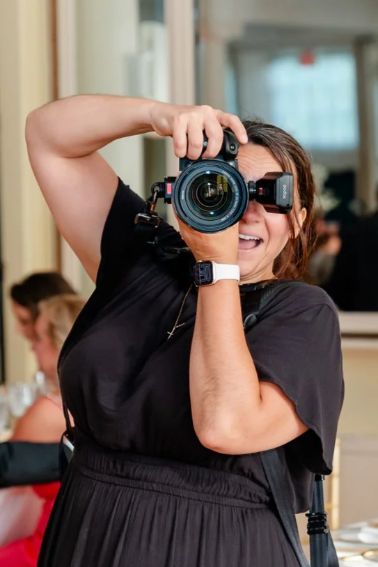 woman taking a photo with a large camera in an indoor setting