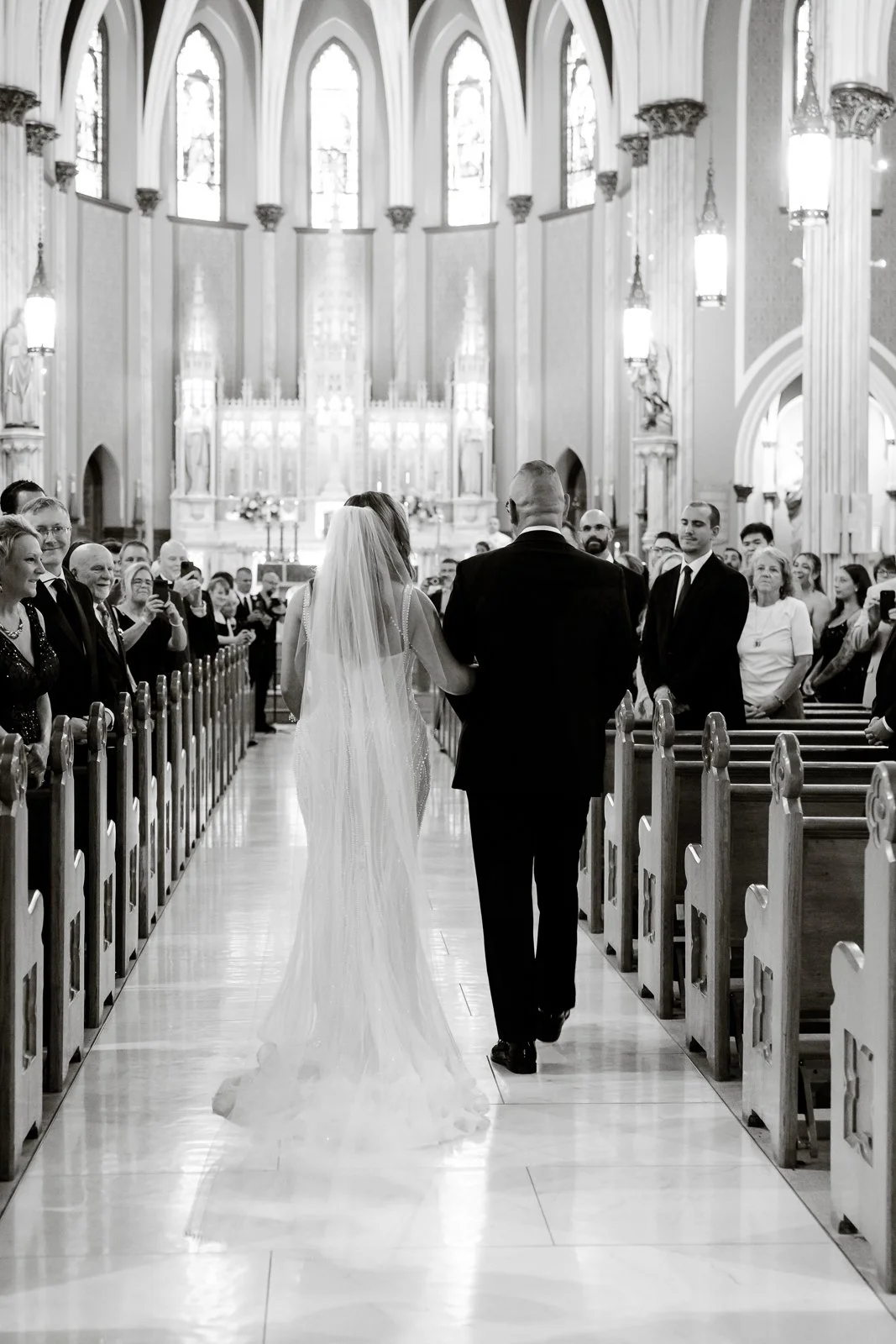 Bride and groom walking down the aisle of a church after their wedding ceremony, with guests on either side of the pews.
