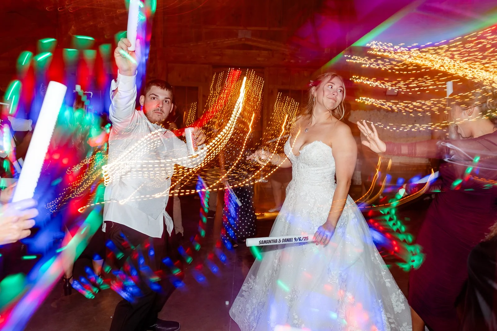 People dancing at a wedding reception with colorful lights and motion blur effects.