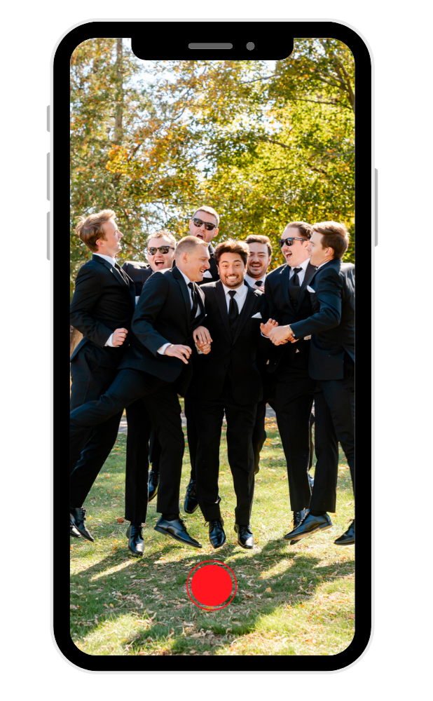Group of men in suits standing outdoors under trees, laughing and celebrating, with a phone graphic overlay showing their photo.