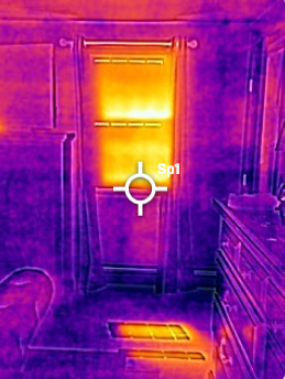A door with a window at the top, illuminated by a warm yellow light, in a room with wooden furniture and a visible radiator cover on the floor.