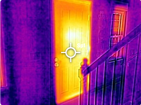 Infrared thermal image of a room showing a door and staircase, with colors indicating heat levels: yellow on the door indicating warmth, purple on the walls and staircase indicating cooler temperature.