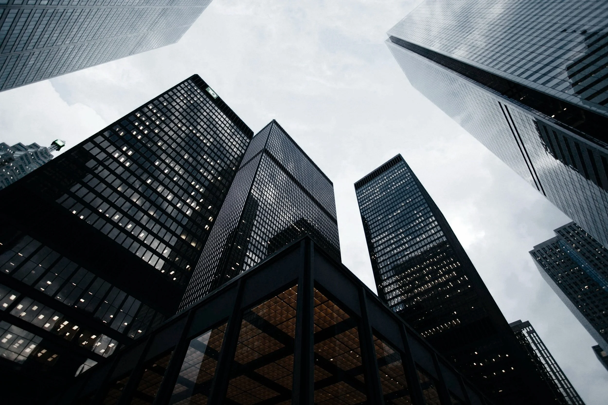 Looking up at tall modern skyscrapers against a cloudy sky in an urban city