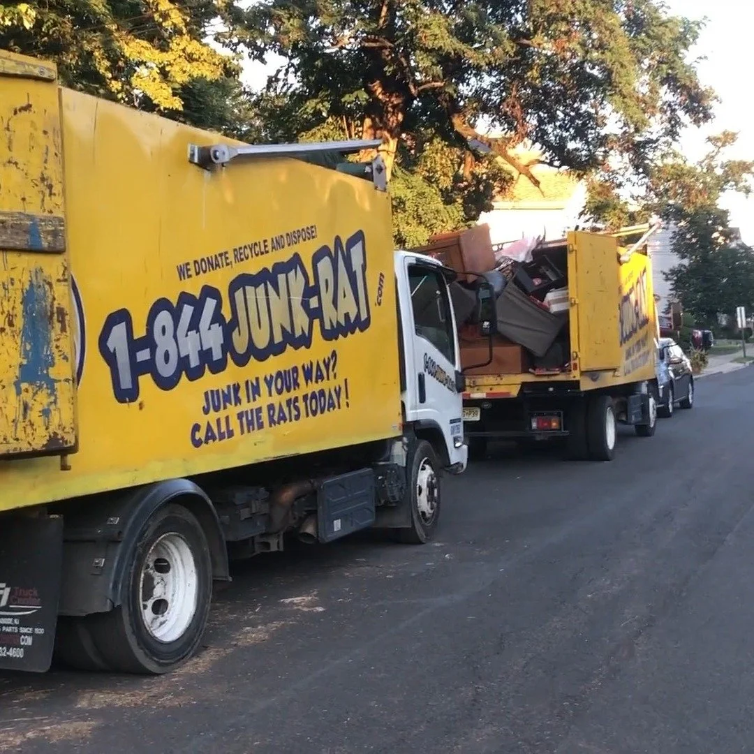 Yellow junk removal trucks with debris loaded, parked on a suburban street with trees in the background, advertising a junk removal service.