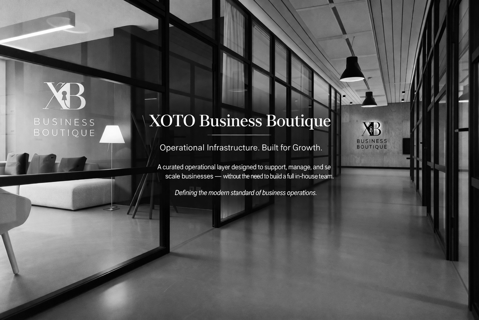 Black and white interior of a modern business office with glass walls, a waiting area with chairs, a lamp, and text on the glass reading 'XOTO Business Boutique' and 'Operational Infrastructure. Built for Growth.'
