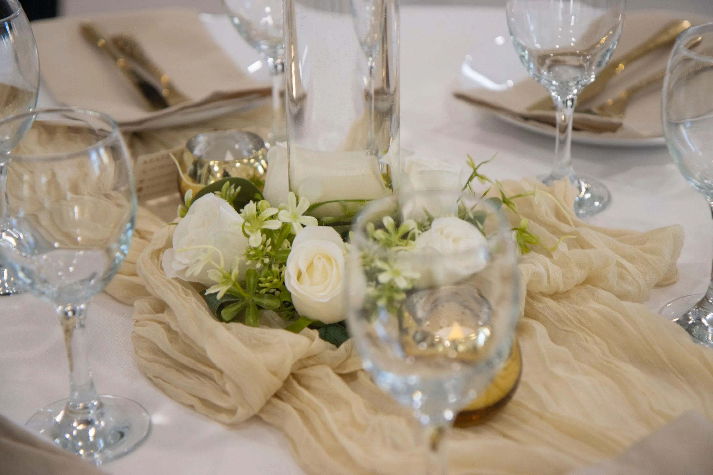 Table élégante avec centre de table floral blanc, verres à vin et bougies à la fête.
