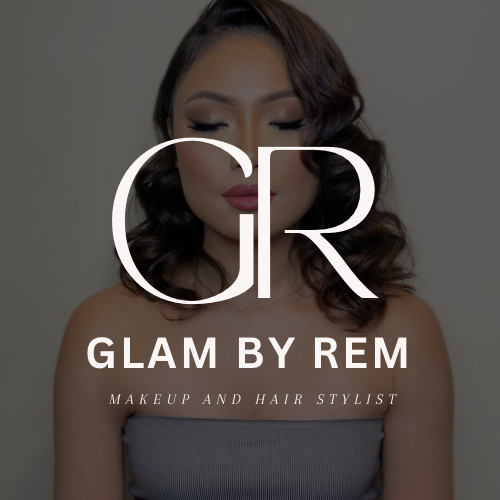 Une femme avec des cheveux bouclés portant des vêtements gris, avec le logo 'Glam by Rem' et le texte 'Makeup and Hair Stylist' superposé.