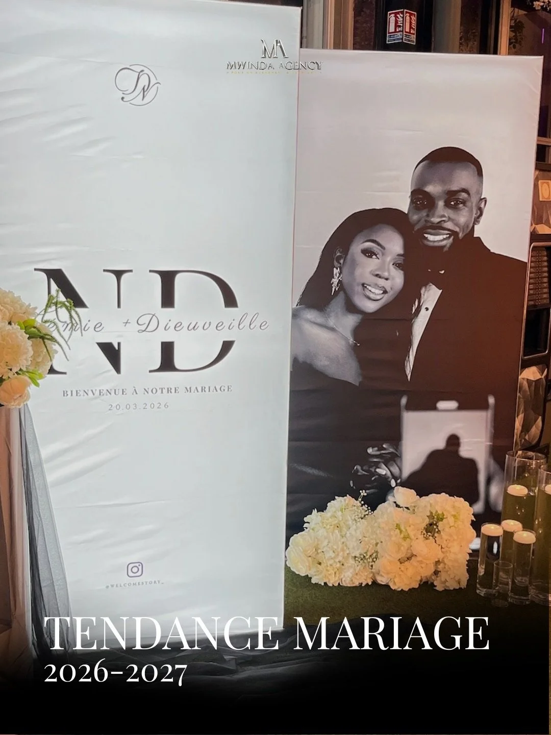 Affiche de mariage avec une photo en noir et blanc d'un couple souriant, décor floral blanc, textes en français et en anglais, annonçant le mariage de Marie et Dieuweille le 20 mars 2026, avec des détails de tendance mariage 2026-2027.
