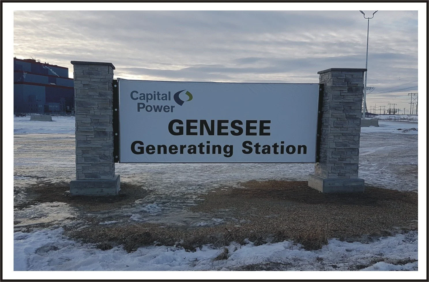 Sign for the Genesee Generating Station operated by Capital Power, with stone pillars and a snowy landscape in the background.