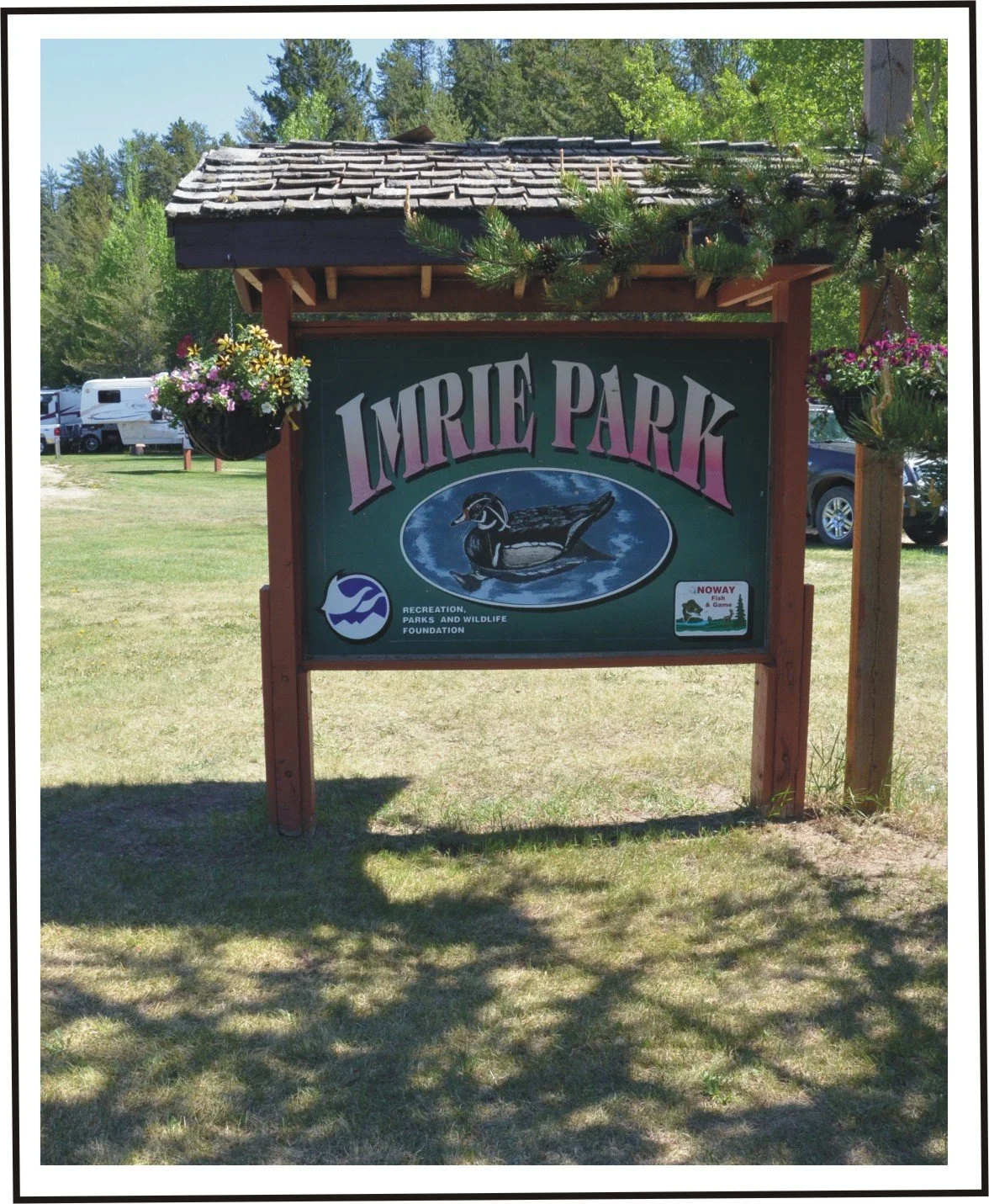 Sign for Imrie Park with a duck illustration and floral decorations around it.