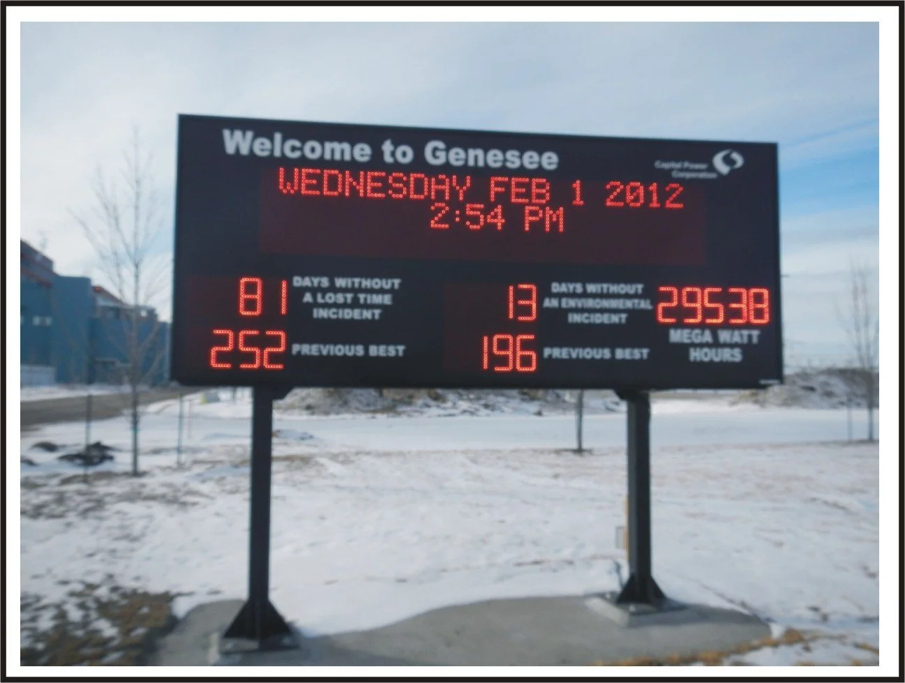Digital roadside sign welcoming to Genesee on February 1, 2012, with weather and traffic statistics displayed, in snowy environment.