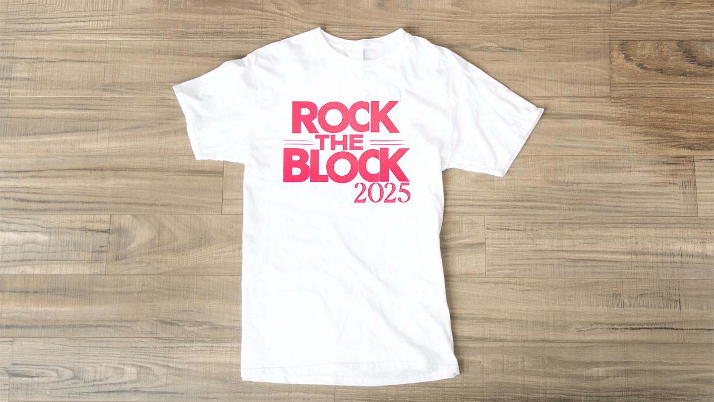 Custom t-shirt design for Rock the Block 2025 — bold red 'ROCK THE BLOCK 2025' text on a white shirt laid flat on a wood floor. Clean, energetic event design by Heather at Genuine Midwest Consulting