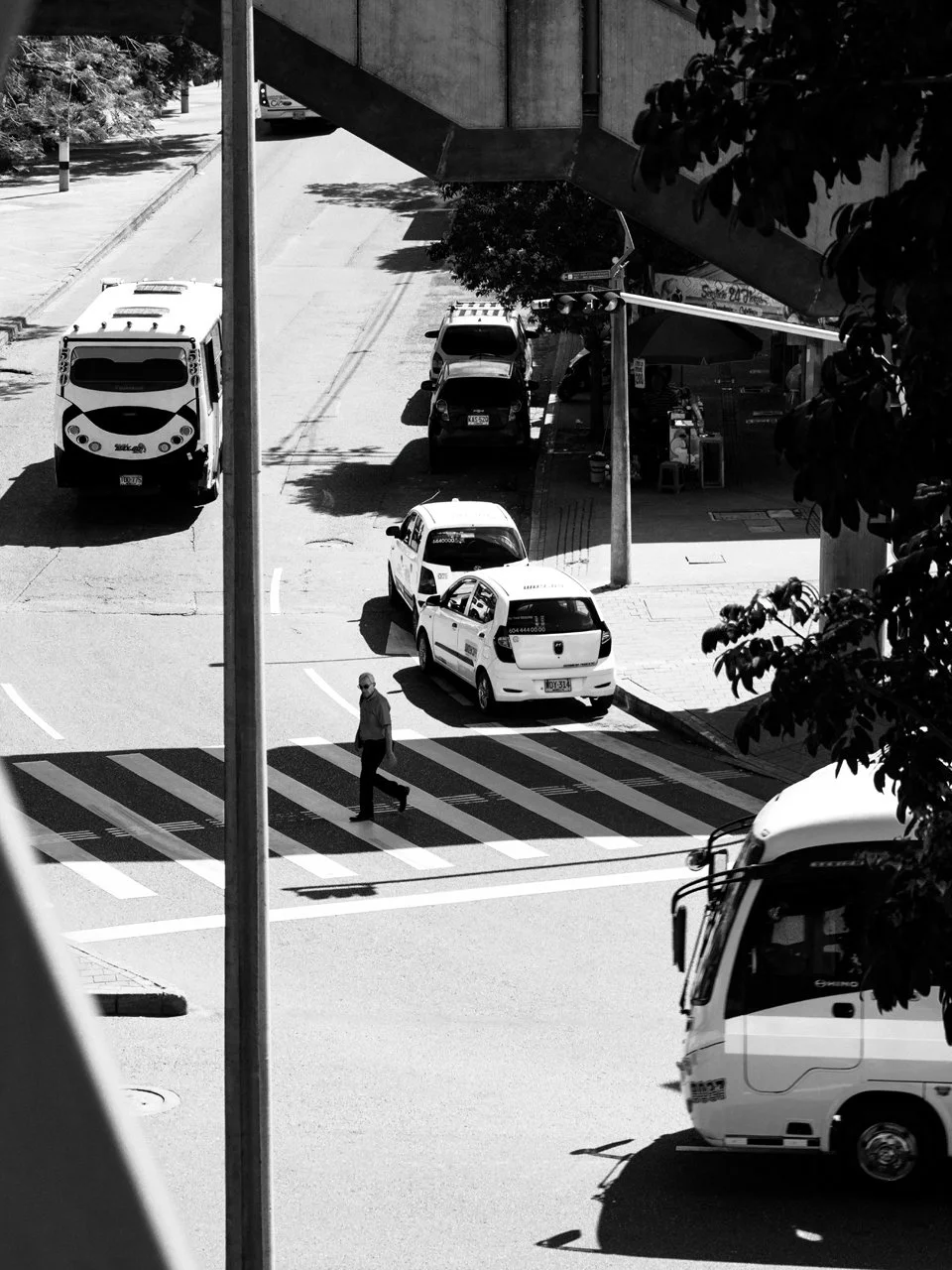 Black and white street photo of a person walking across a road in Medellin, Colombia.