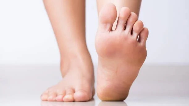 Close-up of a person stretching their barefoot foot, with the other foot flat on the ground.