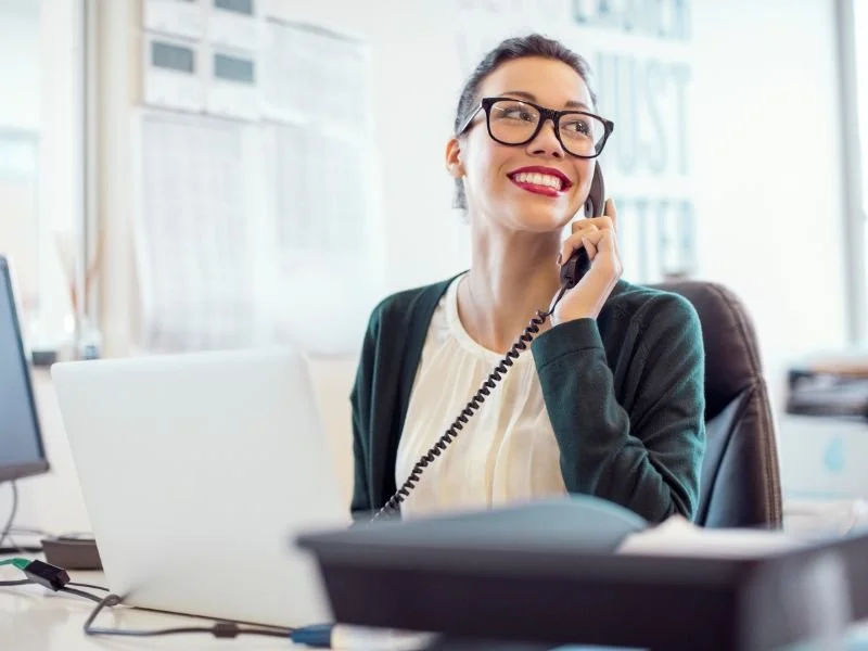 A receptionist taking a phone call on an NEC phone system landline