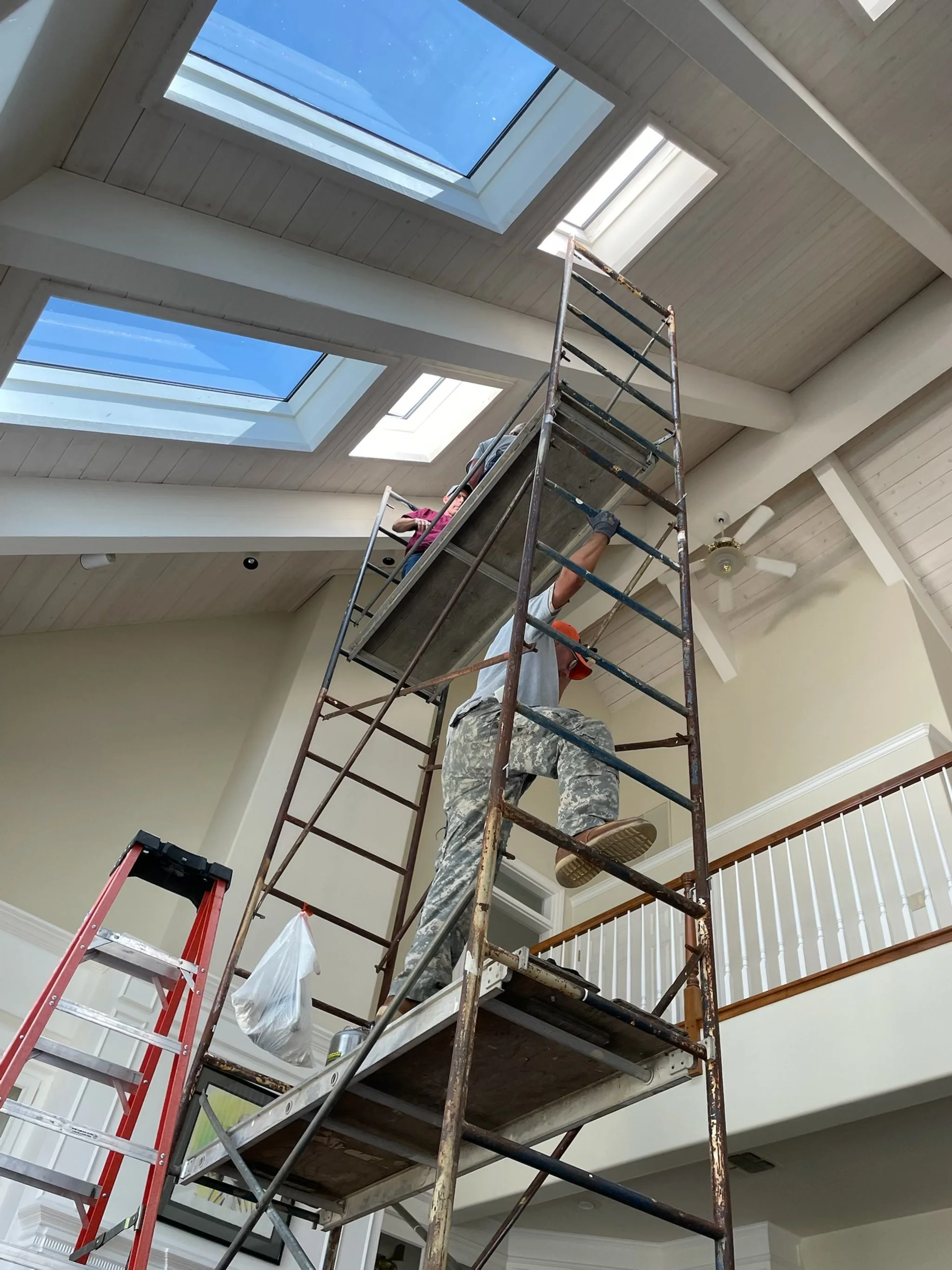Workers on scaffolding installing or repairing skylights in a ceiling.