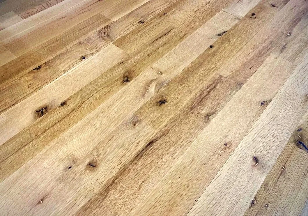 Close-up view of a wooden floor with natural light and visible wood grain, knots, and texture.