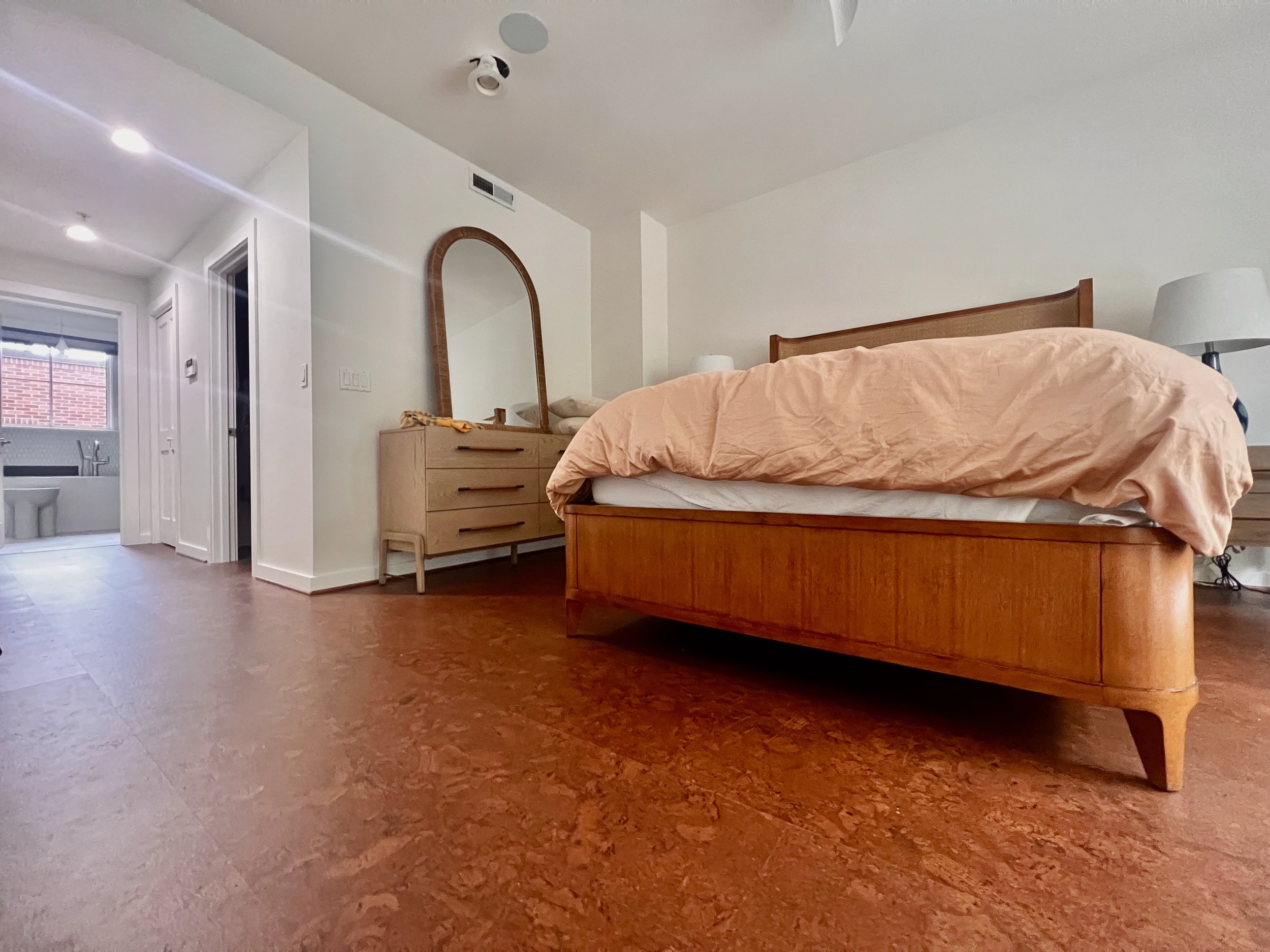 A bedroom with light brown, warm cork flooring.