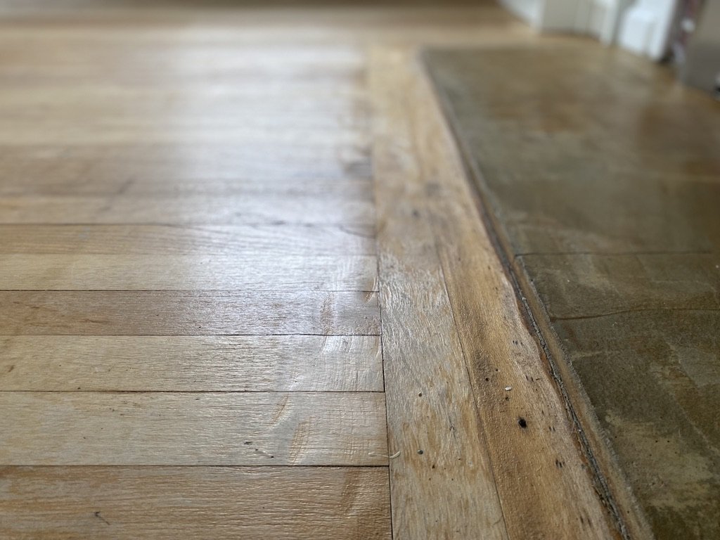 Close-up of a transition between hardwood flooring and tile flooring in a home.