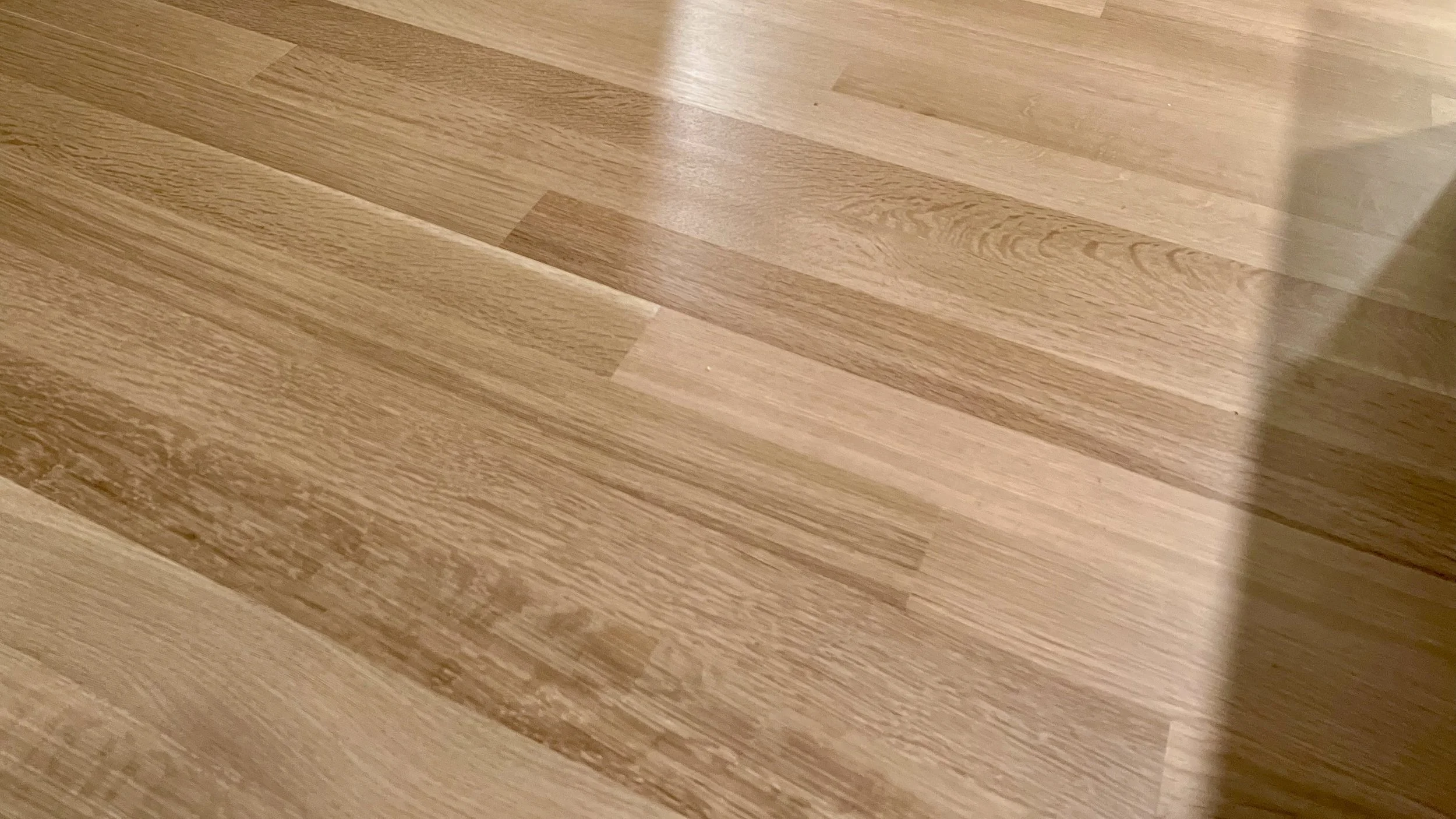 Close-up of a wooden hardwood floor with a shadow cast on the right side.