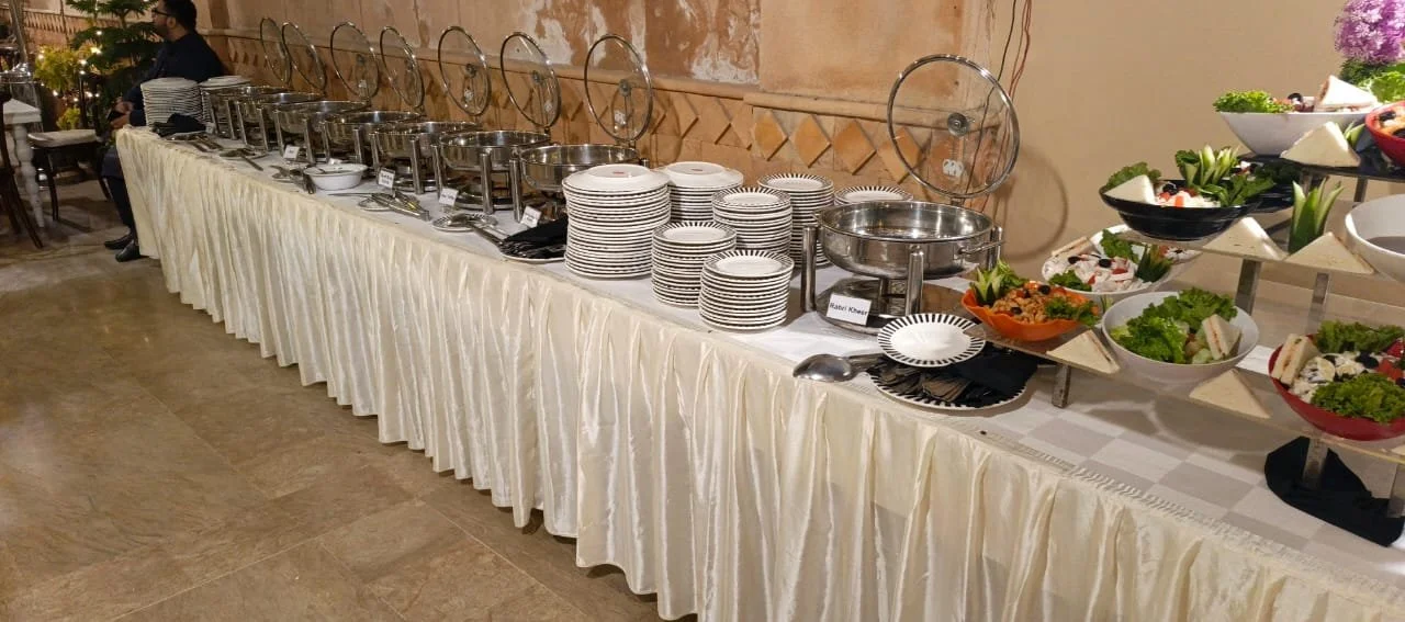 Buffet table with chafing dishes, plates, bowls, and salad area in a restaurant setting