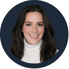 Portrait of a young woman with long dark hair, wearing a white turtleneck sweater, smiling against a dark background.