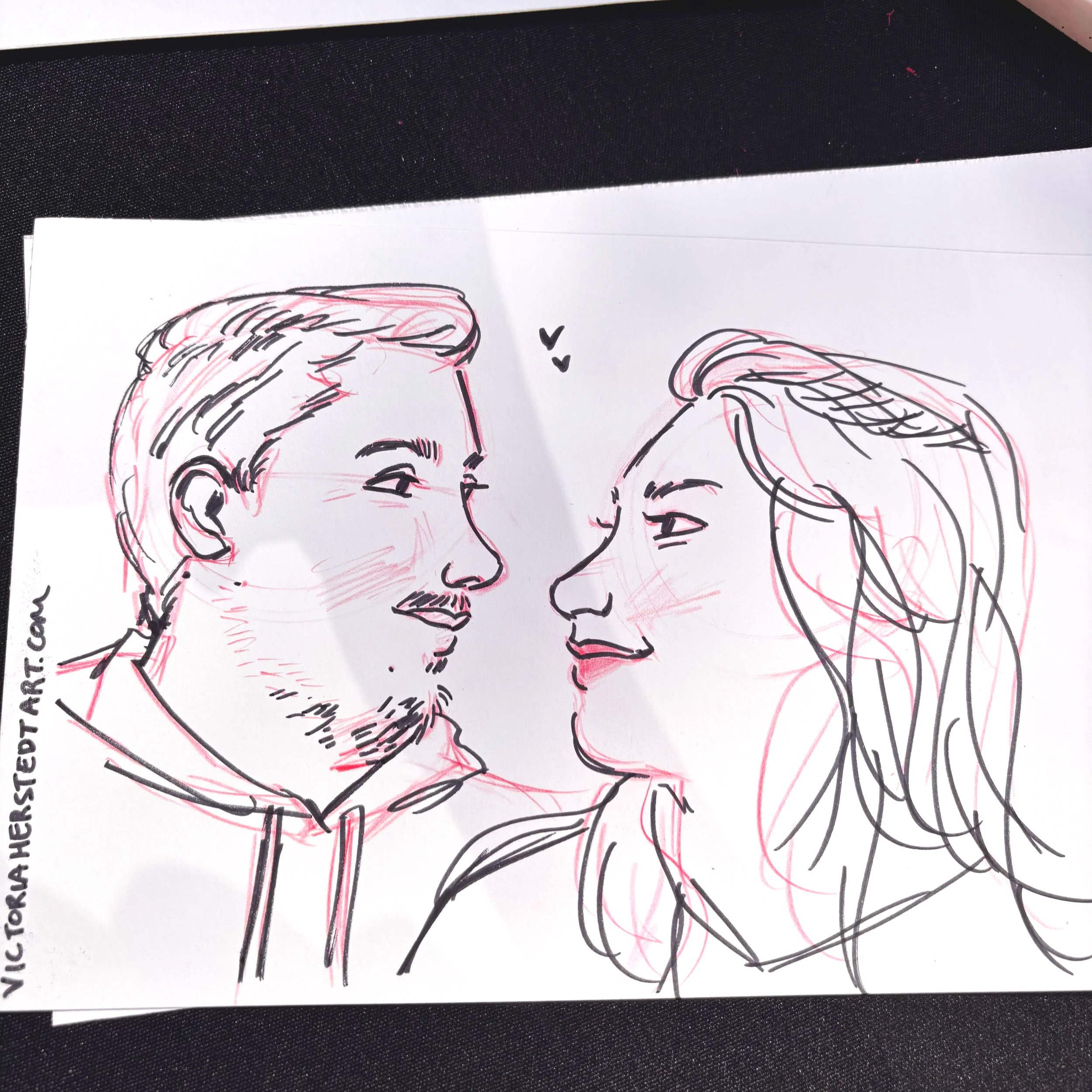 A drawing of a couple (man and a woman) in ink pen and red colored pencil done at an alternative wedding expo at the Victorian Belle.