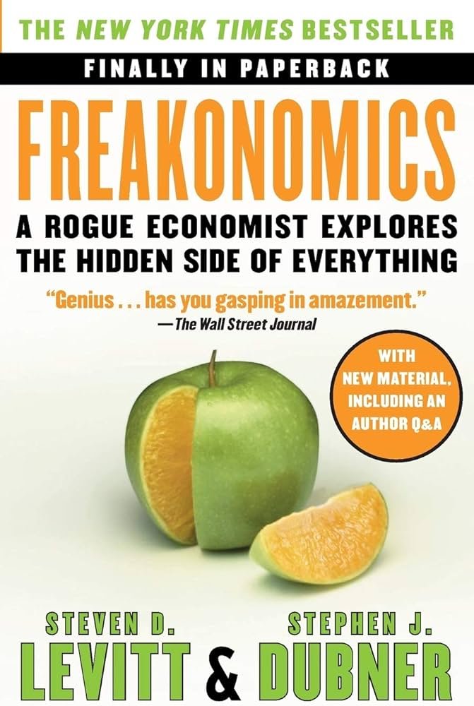 Book cover of "Freakonomics" by Steven D. Levitt and Stephen J. Dubner, with a partially peeled green apple revealing an orange inside, and a slice of orange beside it.
