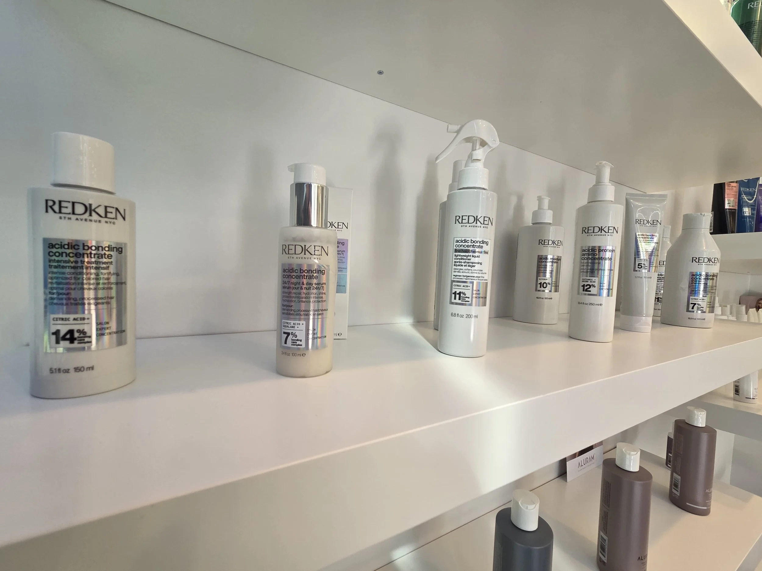 Shelf displaying various bottles of Redken hair care products in a salon.