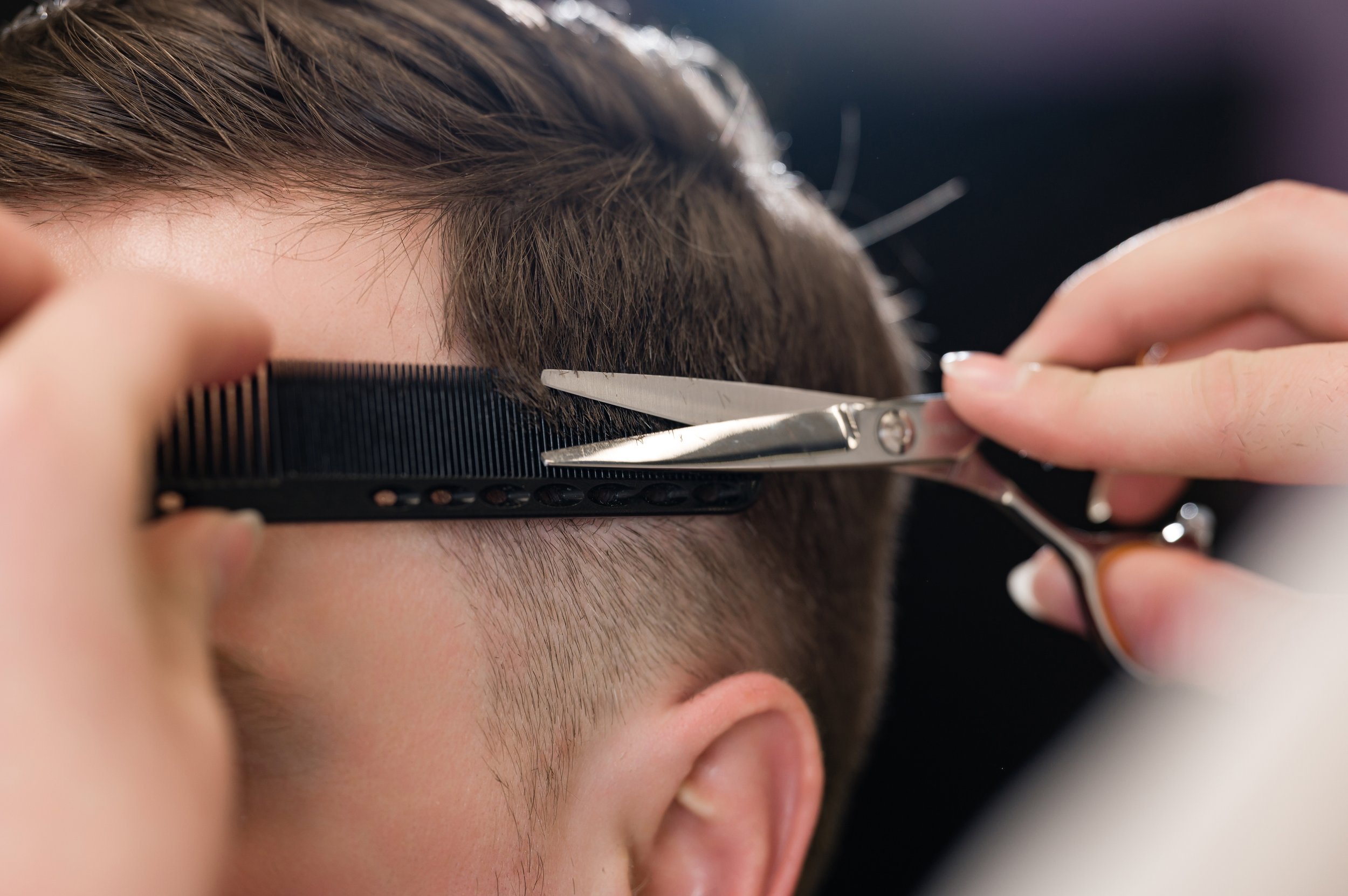 Person getting a haircut with scissors and comb.