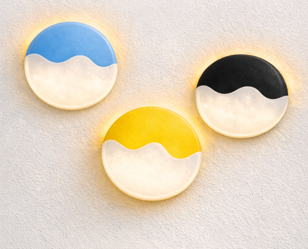 Three circular wall lights with wave patterns, one blue, one black, and one yellow, mounted on a textured white wall, illuminated to create a warm glow.