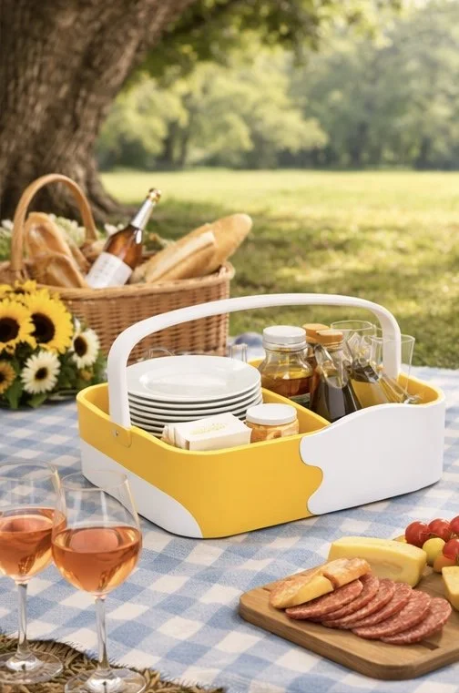 Picnic basket with bread, drinks, and snacks on a table outdoors.