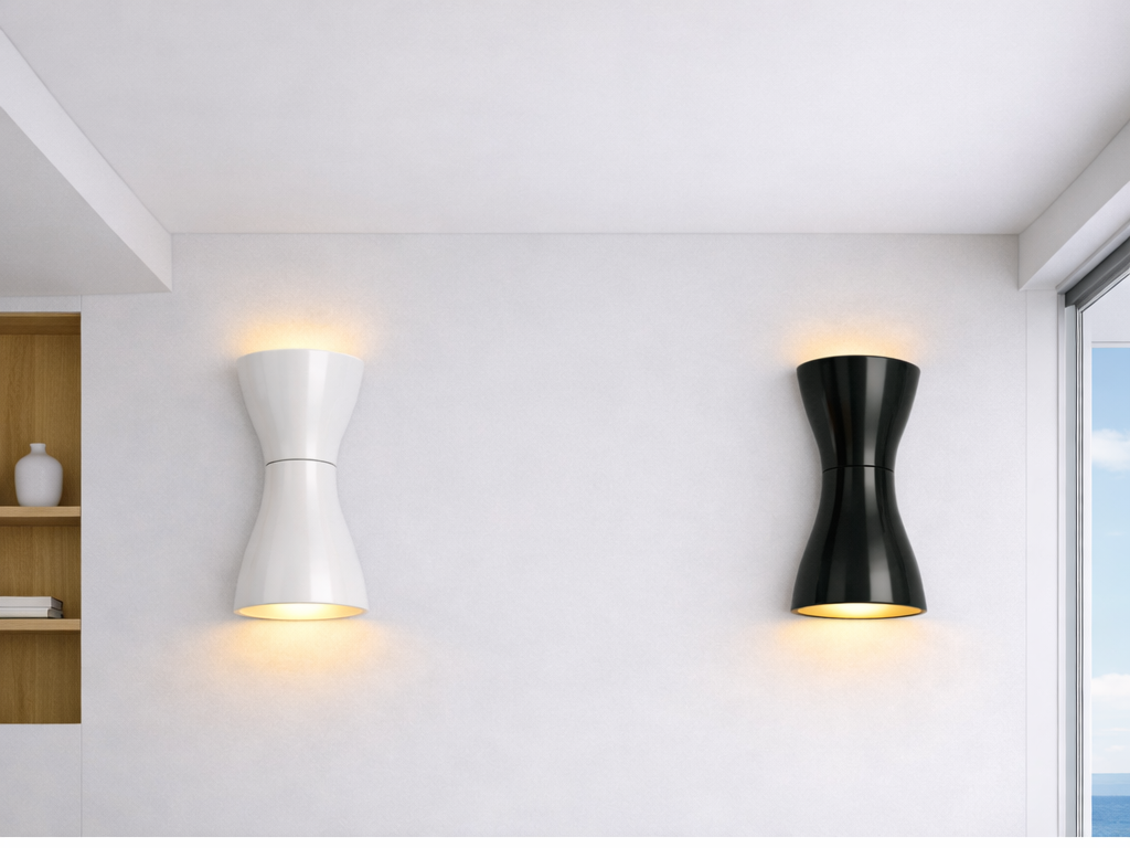Two modern wall sconces, one white and one black, mounted on a white wall with lighting directed upward and downward, inside a room with a window showing a blue sky and ocean outside.