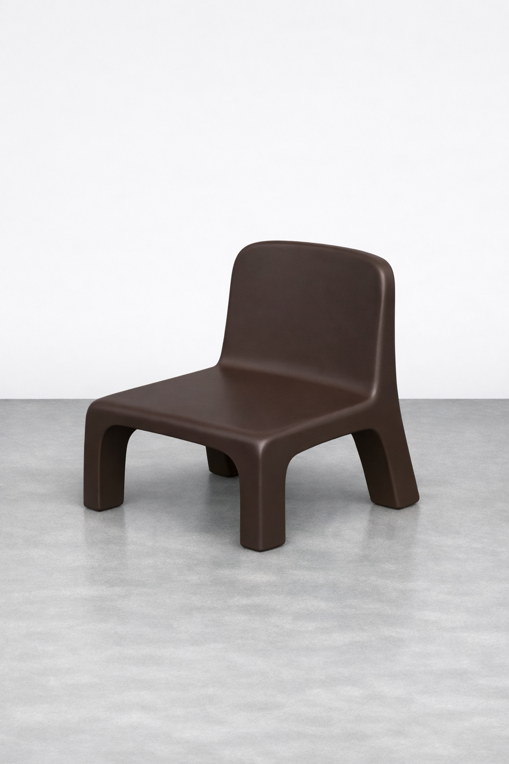 Brown modern chair with rounded edges on a gray floor against a plain white wall.