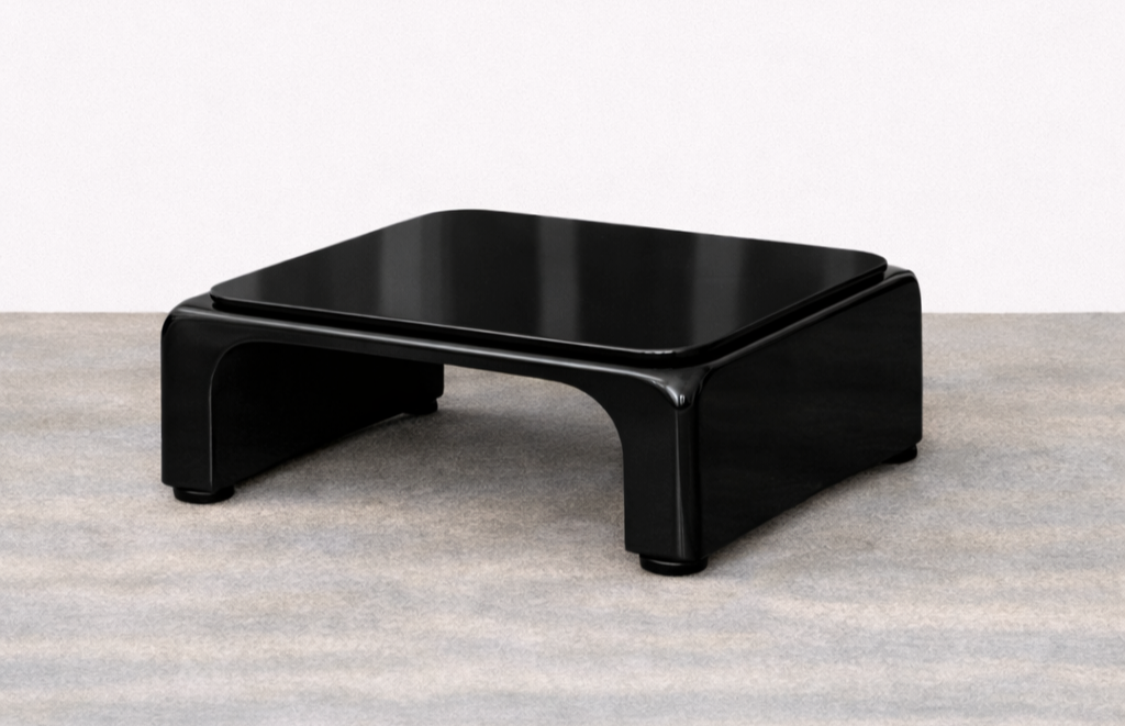A black modern Japanese style low table on a carpeted floor against a white wall.