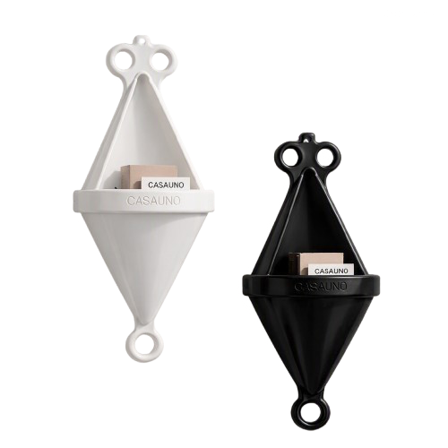 Two diamond-shaped soap dispensers, one white and one black, with a small compartment labeled 'CASAUNO' containing soap refills, mounted on a wall.