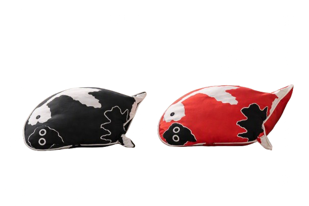 Two fish-shaped pillows, one black and white and the other red and white, on a surface.