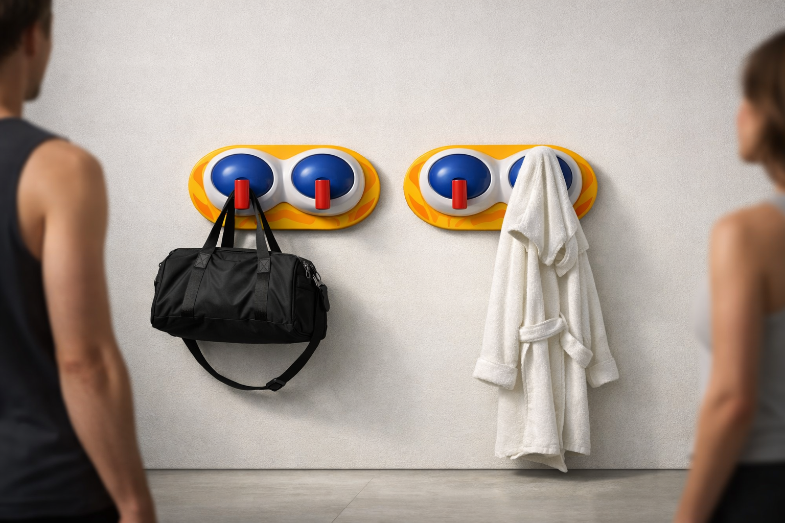 An interior scene showing two wall hooks with a black gym bag hanging on the left hook and a white bathrobe hanging on the right hook, with a wall in the background.
