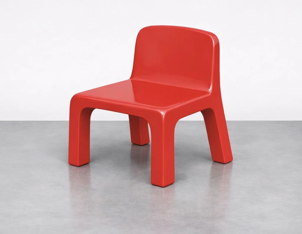 Red plastic chair with a modern design, placed on a gray floor against a plain white background.