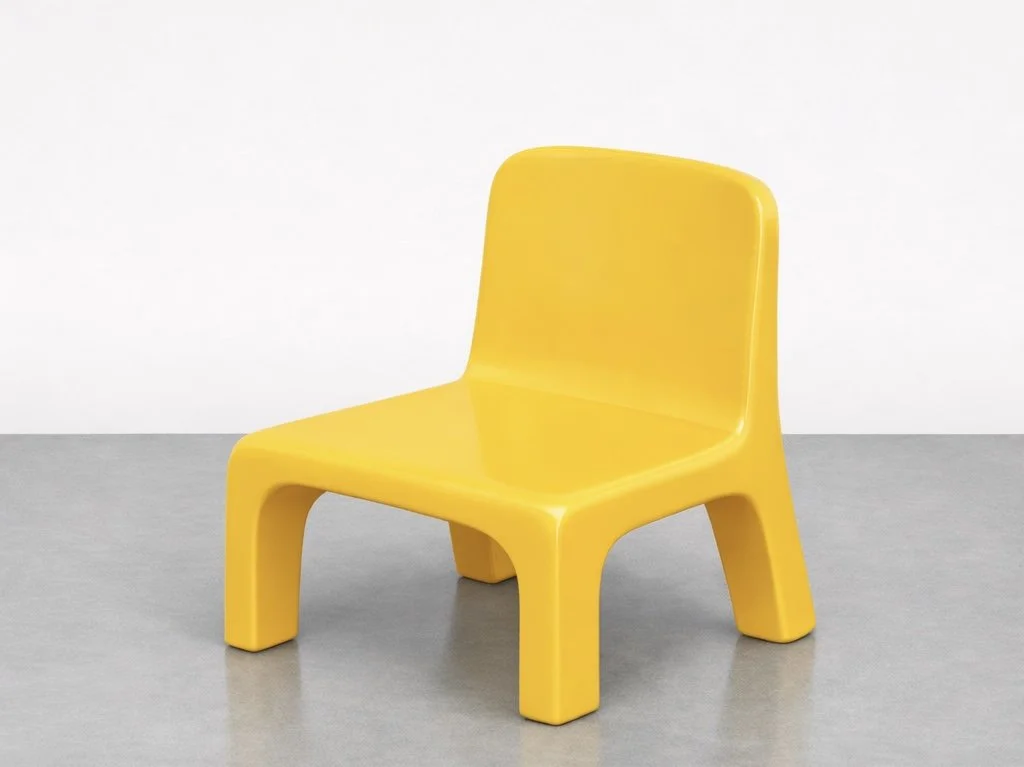 A yellow plastic chair with a simple, modern design, placed on a gray floor against a plain white background.