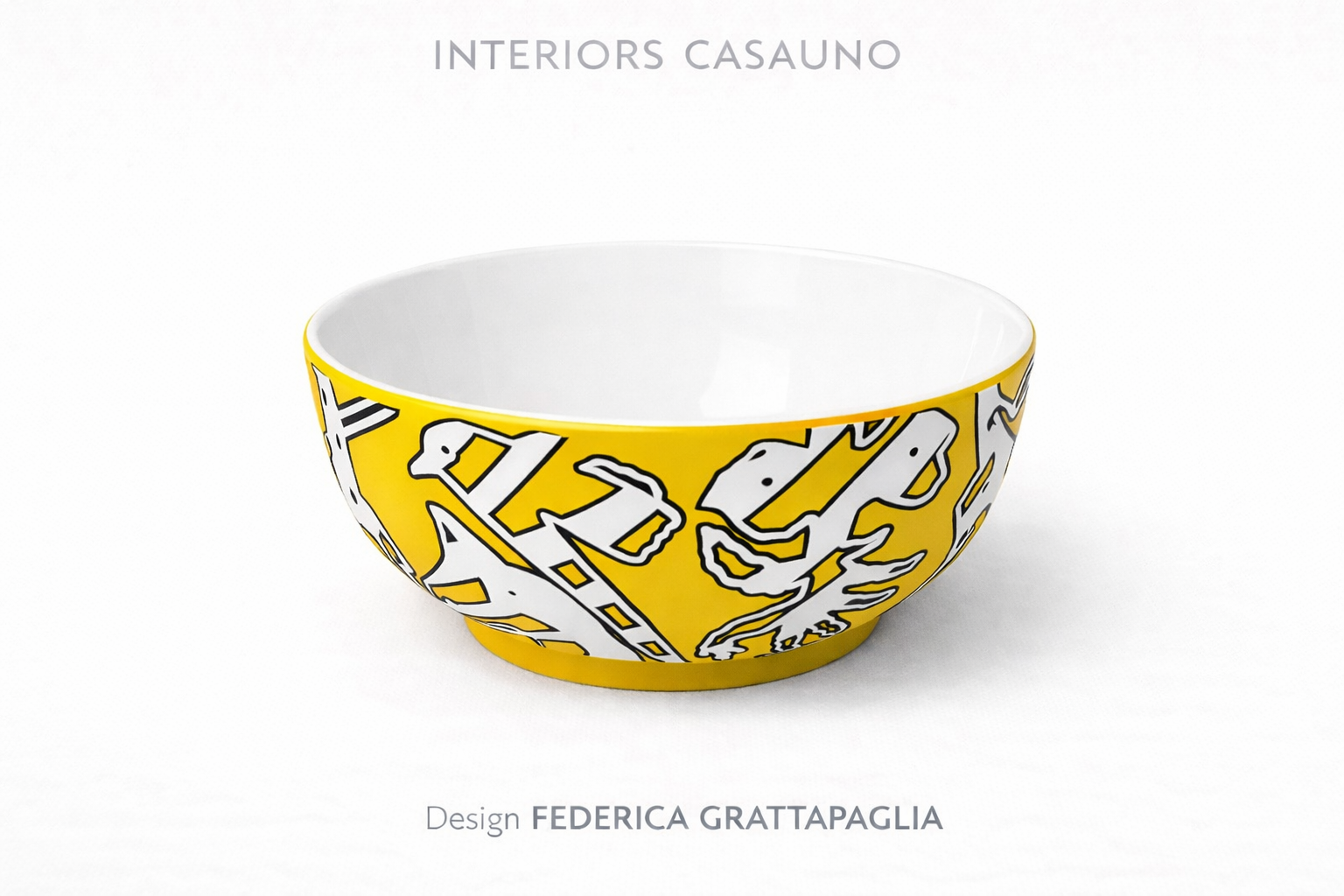 Yellow bowl with black and white graphic design, empty inside, on white background with the text 'INTERIORS CASAUNO' and 'Design FEDERICA GRATTIPAGLIA' above and below.