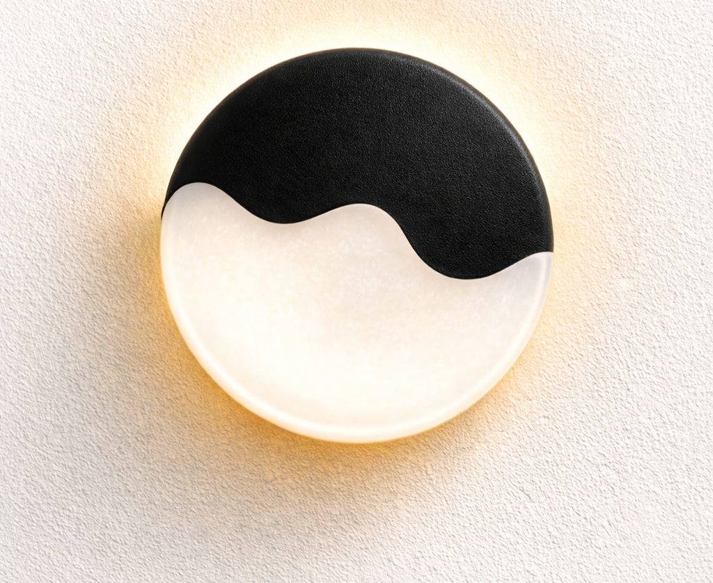 A round wall light with black and white pattern resembling yin-yang symbol mounted on a textured white wall.